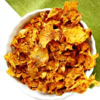 A vertical overhead image of a white bowl filled with Gluten-Free Vegan Dehydrated Sweet Potato Chips on a green napkin on top of a solid white background