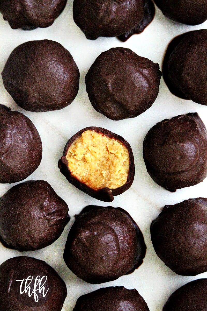 Overhead vertical view of Healthy Gluten-Free Vegan Peanut Butter Bon Bons (aka Reese's Vegan Peanut Butter Eggs) showing the inside of one on a white marble surface