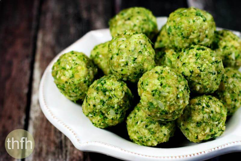 Horizontal view of white bowl full of Gluten-Free Vegan Raw No-Cook Broccoli Balls on a wooden surface