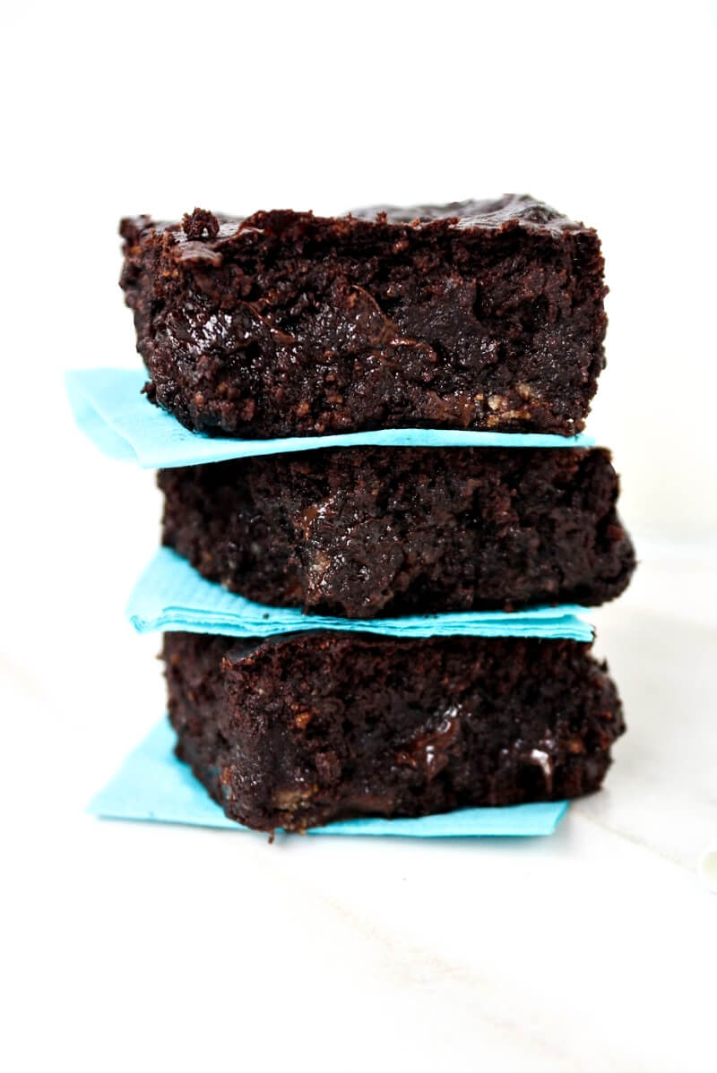 A stack of three of The BEST Gluten-Free Vegan Flourless Zucchini Brownies on a solid white background