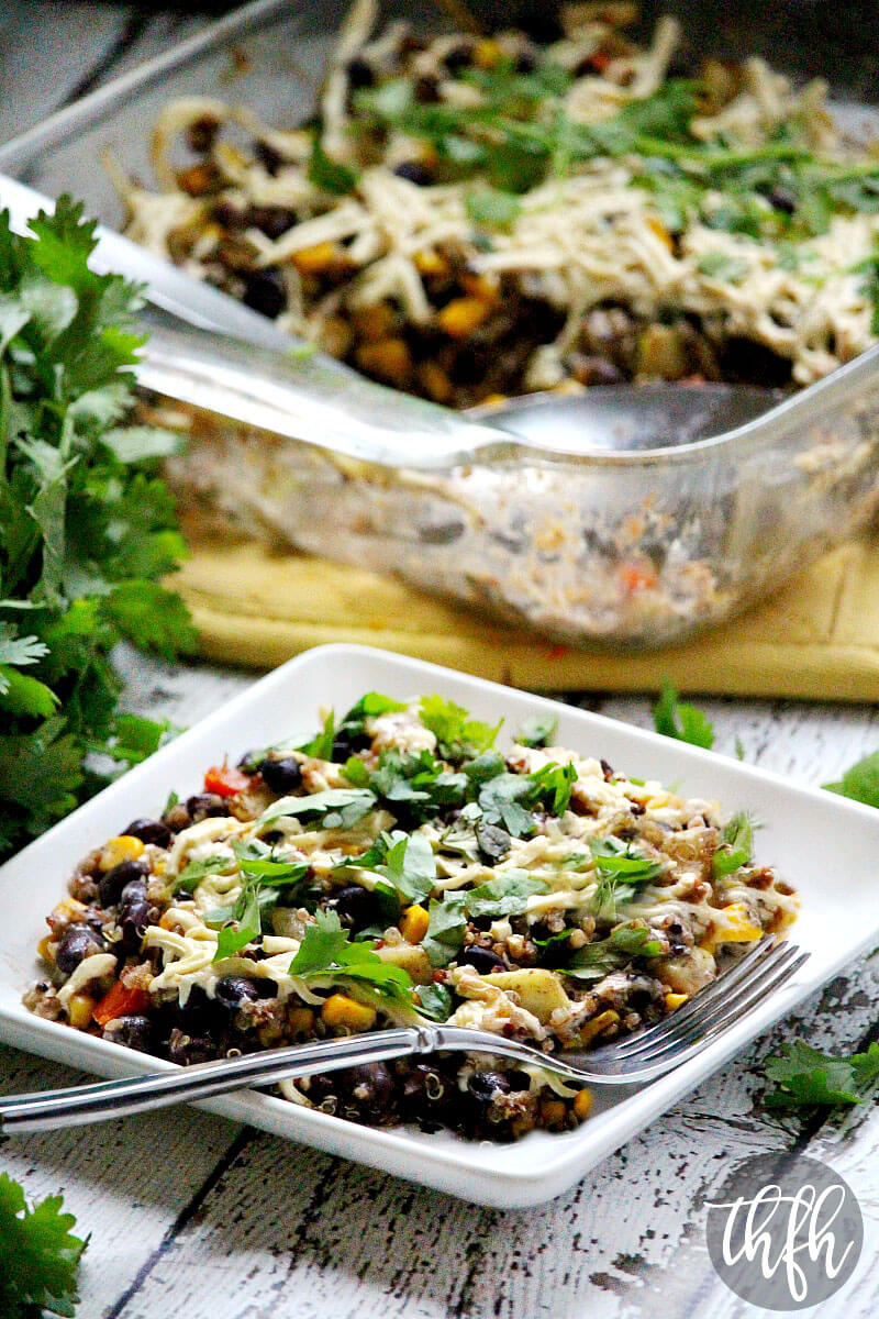 Vertical image of Gluten-Free Vegan Southwest Quinoa Casserole Bake on a white plate on a white wooden surface with baking dish in background