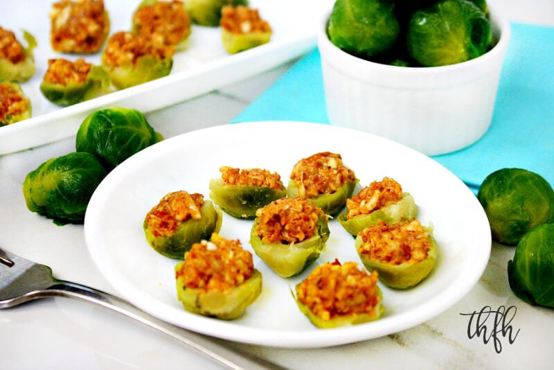 Horizontal image of stuffed Brussels sprouts on a white plate with more in the background on a white platter