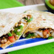 Close up view of two quesadillas on a striped plate on top of a green napkin