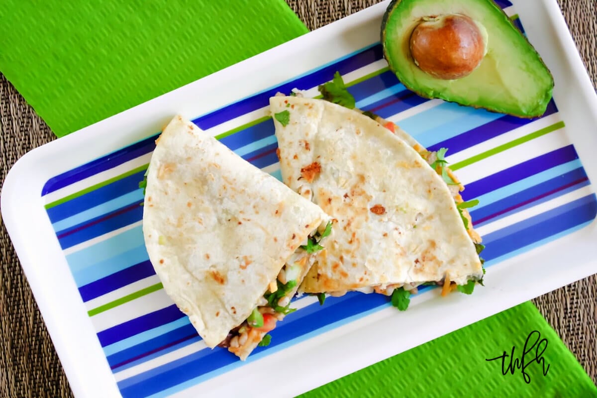 Overhead view of two quesadillas on a striped plate on top of a green napkin