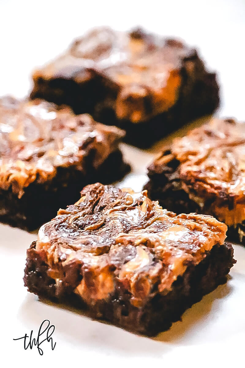 Vertical view of multiple Gluten-Free Vegan Flourless Peanut Butter Swirl Fudgy Brownie on a white surface