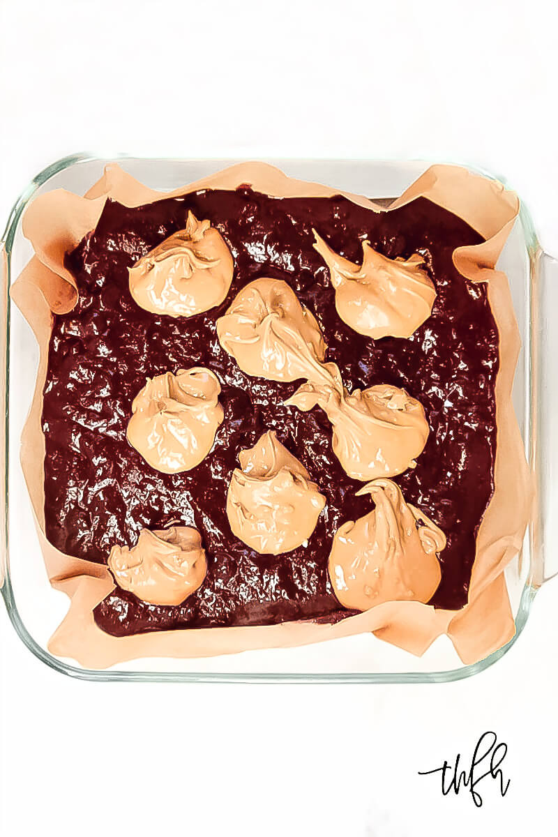 Overhead view of an 8 x 8 glass baking dish with Gluten-Free Vegan Flourless Peanut Butter Swirl Fudgy Brownies with 8 dollops of peanut butter