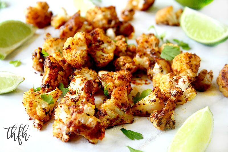 Close up horizontal image of Gluten-Free Vegan Roasted Cauliflower with Chipotle and Lime on a white marble surface with sliced limes