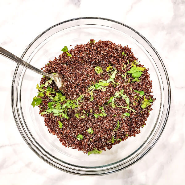 Step-by-step photos showing how to make Red Quinoa with Cilantro and Lime by mixing all ingredients together in a medium-sized mixing bowl