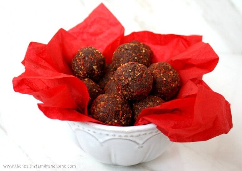 Clean Eating Gluten-Free Vegan Goji Berry and Hazelnut No-Cook Cacao Truffles in a white bowl with red tissue paper on a marble background