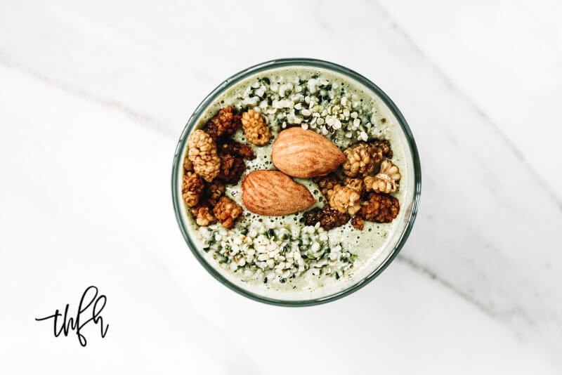 Overhead view of a glass of Gluten-Free Vegan Mango and Hemp Seed Smoothie on a white marble surface