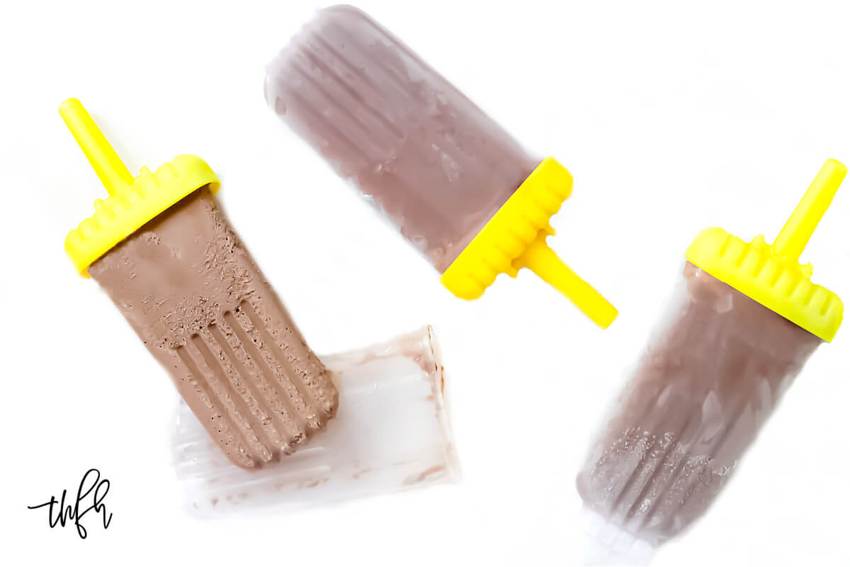 Three chocolate fudgesicles laying on a solid white background