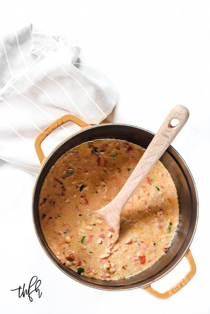Overhead image of a yellow pot filled with chickpea soup with a wooden spoon sticking out