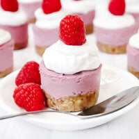 Vertical image of a Gluten-Free Vegan No-Bake Raspberry Mini Cheesecake on a white saucer with silver spoon