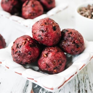 Horizontal image of four red truffles in a small decorative bowl on a weathered wood background