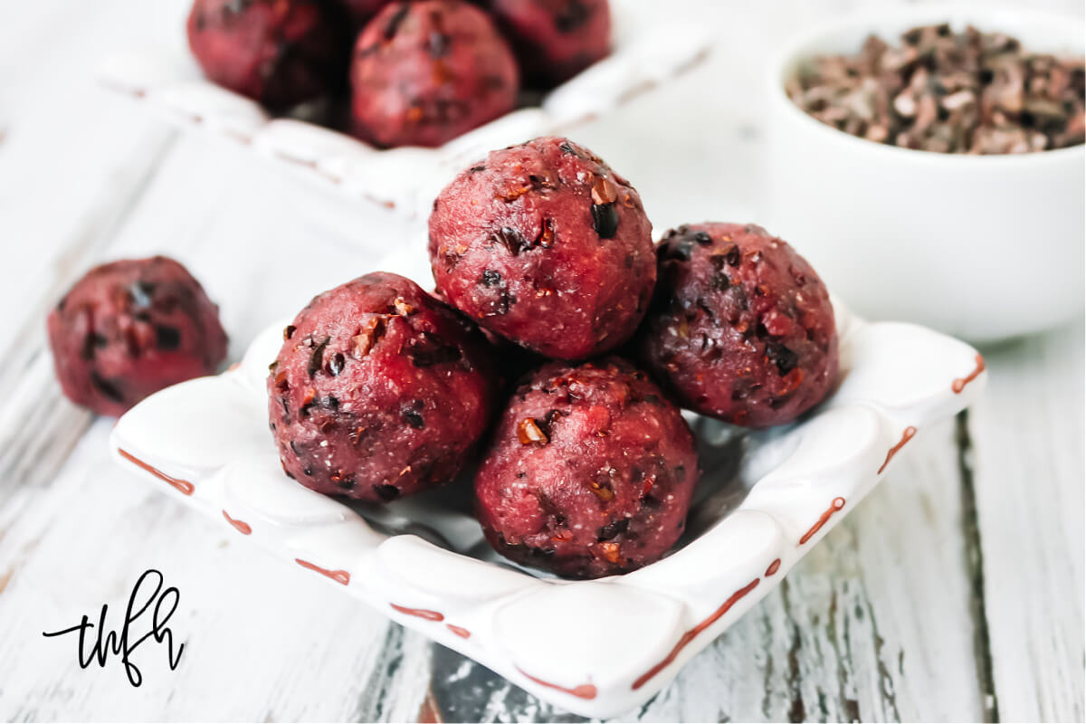 Horizontal image of four red truffles in a small decorative bowl on a white weathered surface