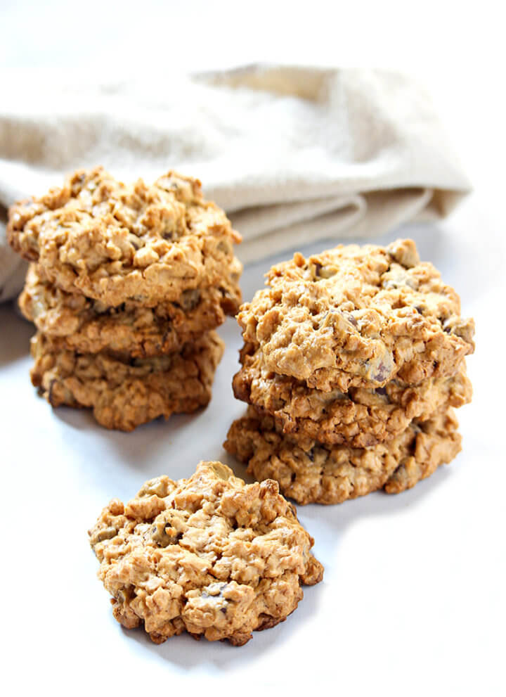 Vertical image of stacks of Gluten-Free Vegan Peanut Butter Chocolate Chip Oatmeal Cookies on a white surface