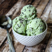 Horizontal image of a small decorative bowl filled with a green vegan superfood ice cream on a weathered wooden surface