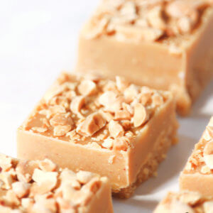 Several squares of peanut butter fudge lined up on a solid white background