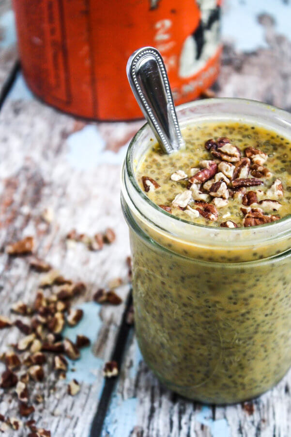 Vertical image of a glass mason jar filled with Gluten-Free Vegan Pumpkin and Pecan Chia Pudding with a silver spoon inserted in the glass