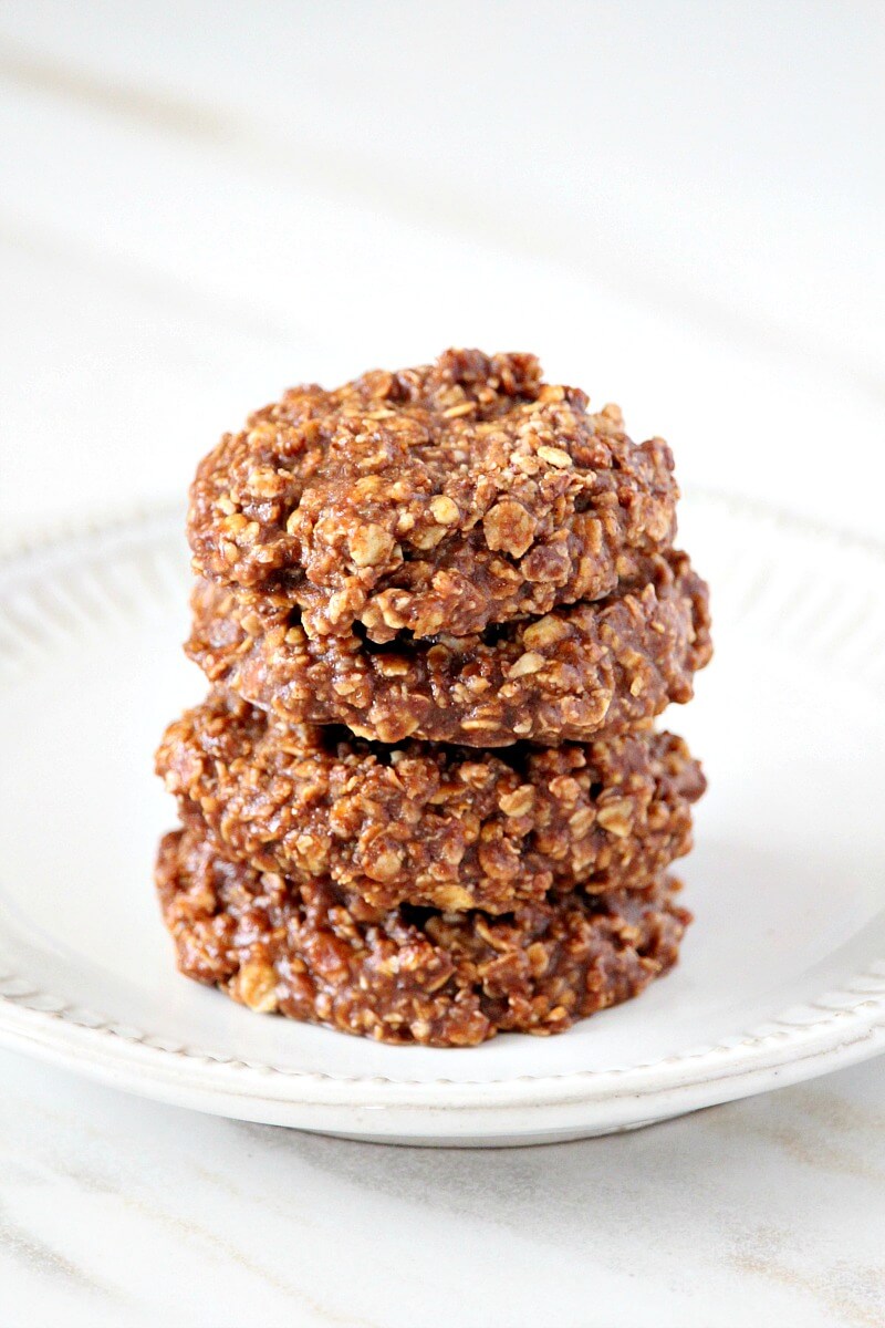 Stack of 4 of The ORIGINAL Healthy Gluten-Free Vegan No-Bake Chocolate Peanut Butter Oat Cookies on a white plate on top of a white marble surface