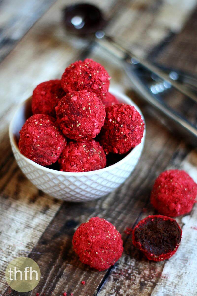 Clean Eating Gluten-Free Vegan No-Cook Strawberry Fudge Truffles in a white bowl on a wooden background with a cookie scoop to the side