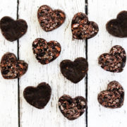 Overhead image of multiple chocolate hearts scattered over a white weathered surface