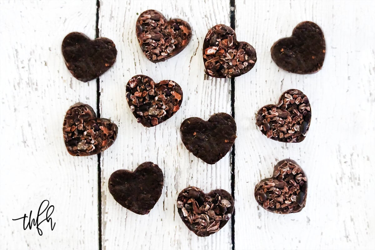 Overhead image of multiple chocolate hearts scattered over a white weathered surface