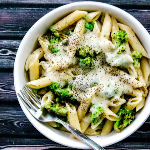 Overhead view of Gluten-Free Vegan Broccoli Alfredo with Creamy Cauliflower Sauce in a white bowl on a black wooden surface