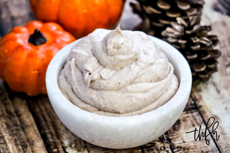 Horizontal image of The BEST Vegan Pumpkin Spice Mousse in a small white marble bowl on a weathered wooden surface