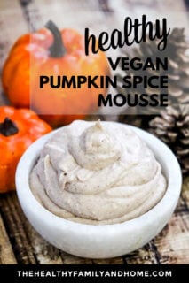 Vertical image of a small white marble bowl filled with The BEST Vegan Pumpkin Spice Mousse surrounded by small pumpkins with text overlay