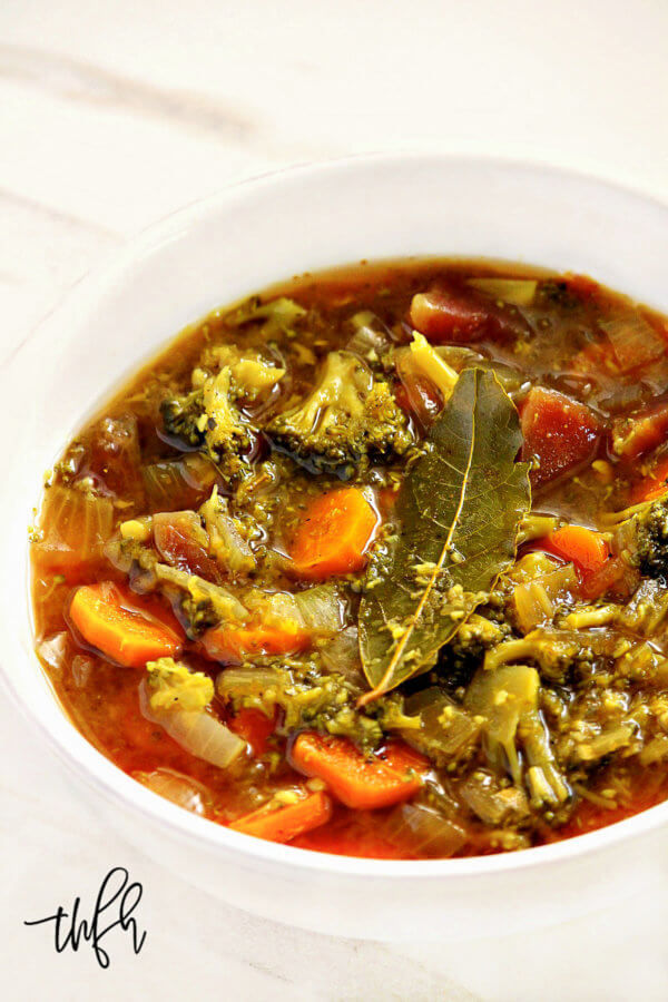 Vertical image of a white bowl filled with Dr. Group's Liver Cleanse Detox Soup on a white marble background