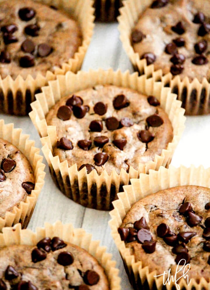 Close-up image of chocolate chip pumpkin spice muffins in a brown paper muffin cup with other muffins surrounding it