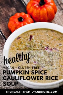 Vertical image of a white bowl filled with creamy Gluten-Free Vegan Pumpkin Spice Cauliflower Rice Soup on a weathered wooden surface with text overlay