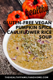 A white bowl filled with Gluten-Free Vegan Pumpkin Spice Cauliflower Rice Soup on a weathered surface with two small pumpkins in the background with text overlay