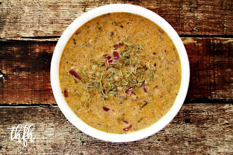 Overhead image of a white bowl filled with Gluten-Free Vegan Pumpkin Spice Cauliflower Rice Soup on a weathered wooden surface