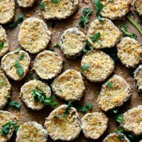 Vertical image of a baking sheet full of Gluten-Free Vegan Oven-Baked "Fried" Pickles on top of parchment paper