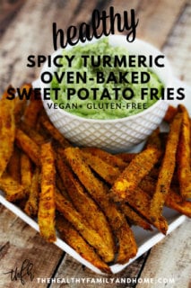 A white plate on a weathered wooden surface filled with Lectin-Free Vegan Spicy Turmeric Oven-Baked Sweet Potato Fries next to a white bowl of avocado dip with text overlay