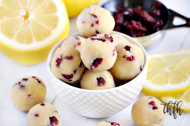 Gluten-Free Vegan No-Bake Cranberry Lemon Ball Truffles in a cream bowl surrounded by lemons and cranberries