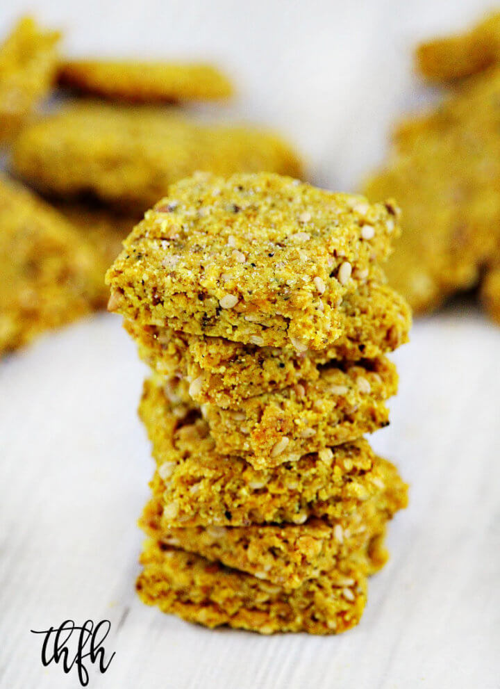 A stack of Gluten-Free Vegan Turmeric and Black Peppercorn Sesame Seed Crackers on a white wooden surface