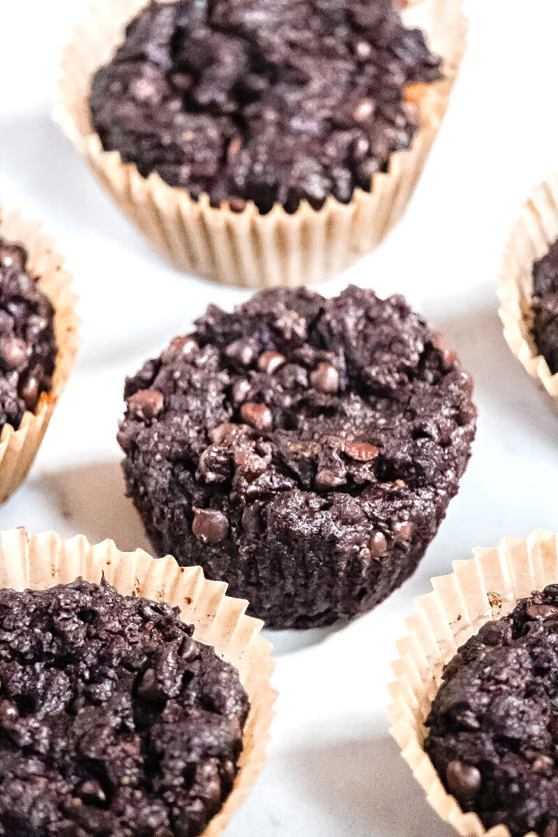 Overhead view of multiple Gluten-Free Vegan Flourless Chocolate Zucchini Muffins in paper muffin cups on a white surface