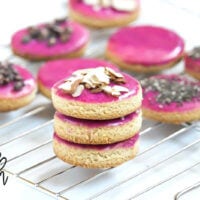 Horizontal view of a stack of 3 Gluten-Free Vegan Flourless Iced Cut-Out Cookies on wire cookie tray on a white surface