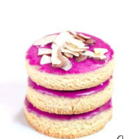 Vertical view of a stack of three Gluten-Free Vegan Flourless Iced Cut-Out Cookies on a wire cookie rack on a white surface