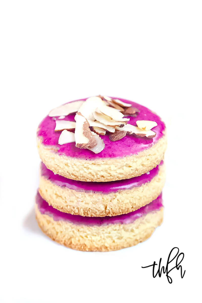 Vertical view of a stack of three Gluten-Free Vegan Flourless Iced Sugar Cut-Out Cookies on a wire cookie rack on a white surface