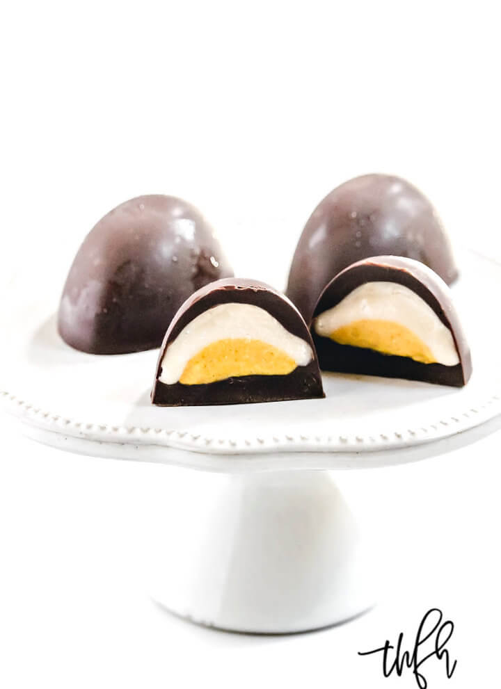 Vertical image of Gluten-Free Vegan Healthy "Cadbury Creme Eggs" on a dessert platter on a white background