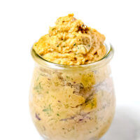 Vertical view of Gluten-Free Vegan Sweet Potato and Cilantro Dip in a glass jar on a white surface