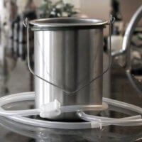 Horizontal view of a stainless steel coffee enema bucket with tubing