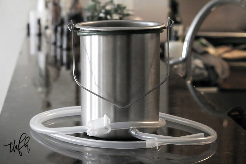 Horizontal view of a stainless steel coffee enema bucket with tubing