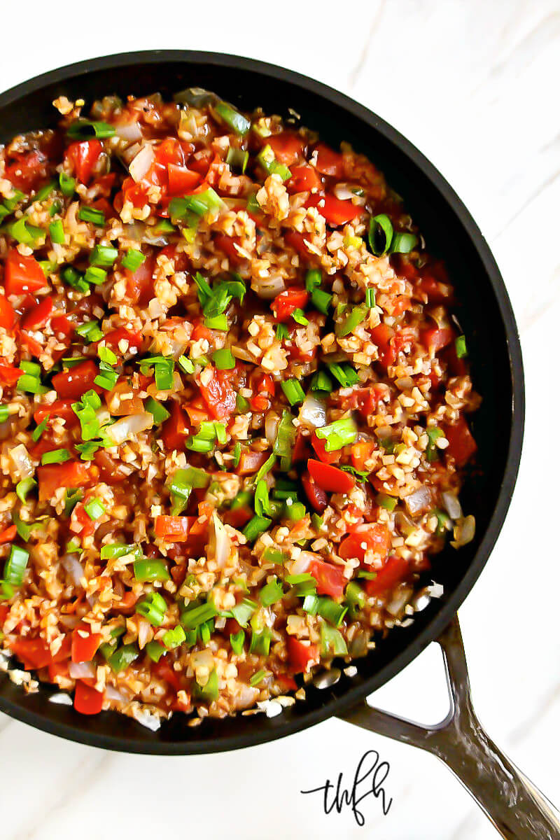 Overhead view of Gluten-Free Vegan Spicy Mexican "Spanish" Cauliflower Rice in a black skillet on a white marbled surface