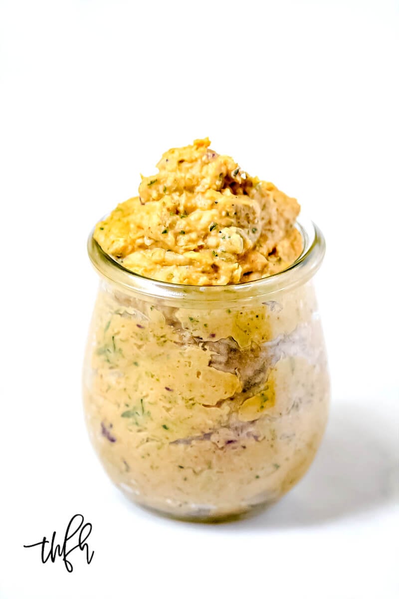 Vertical view of Gluten-Free Vegan Sweet Potato and Cilantro Dip in a glass jar on a white surface