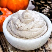 Horizontal image of The BEST Vegan Pumpkin Spice Mousse in a small marble bowl on a weathered wooden surface